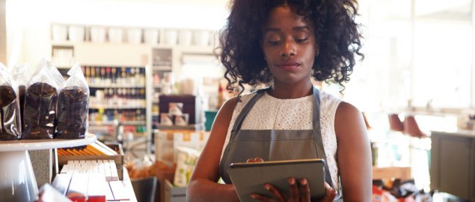 Female business owner researching e-file providers on a tablet in a cafe.