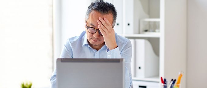 Man at desk in front of computer frustrated