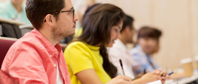College students taking notes in lecture hall